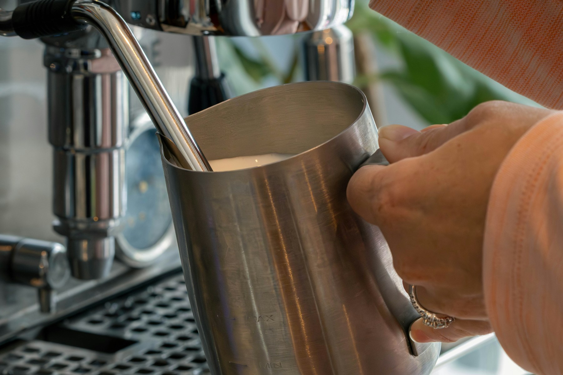 Milk being steamed in a stainless-steel pitcher